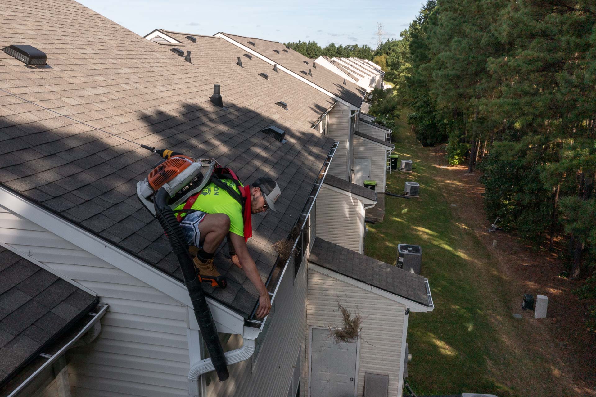 Gutter cleaning professional inspecting gutters on a Huntersville home surrounded by mature oak trees